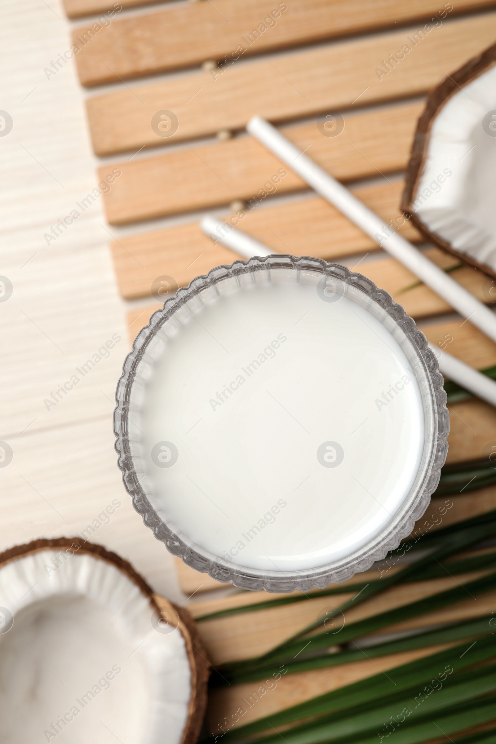 Photo of Glass of delicious vegan milk and coconuts on white wooden table, flat lay