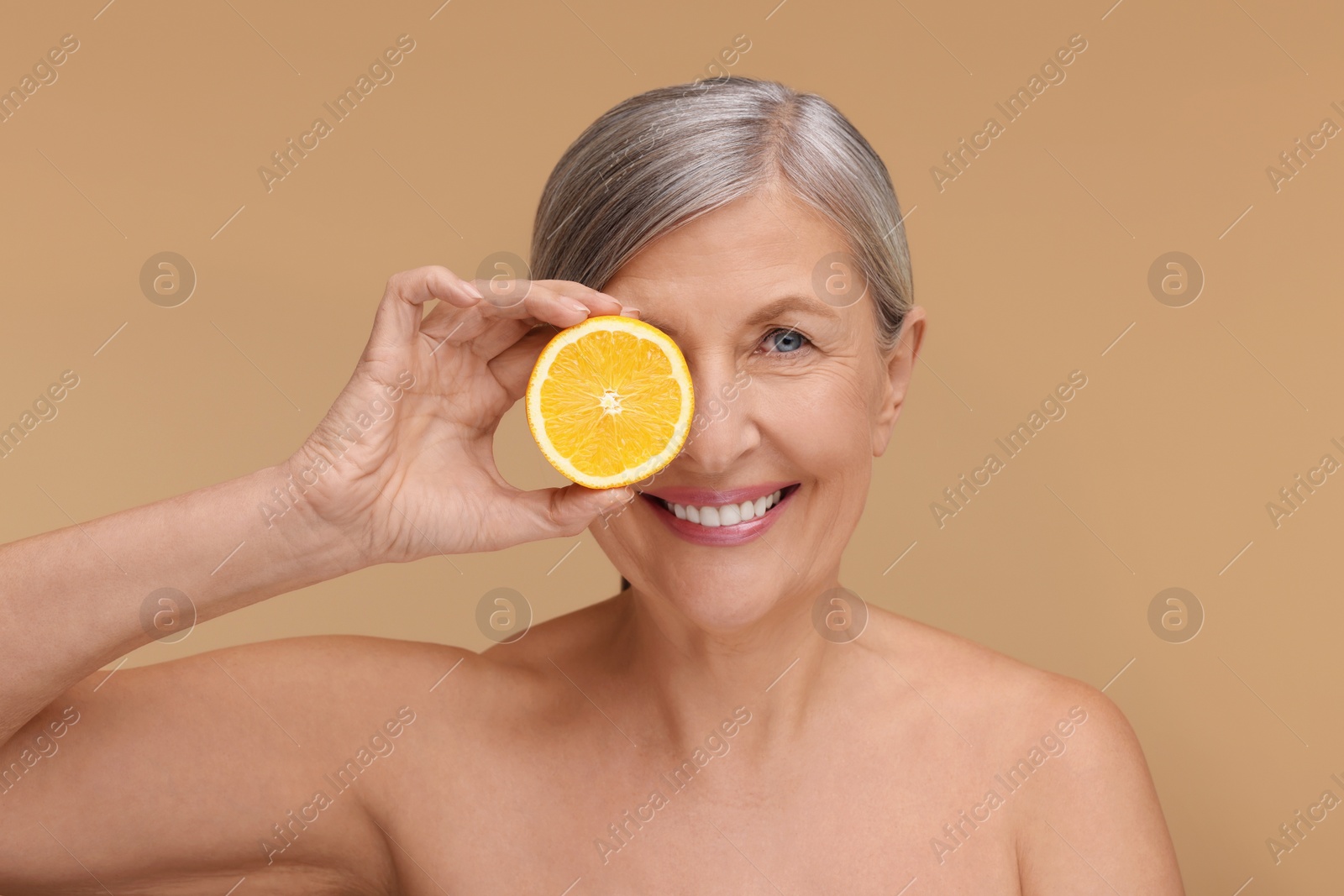 Photo of Beautiful woman with half of orange rich in vitamin C on beige background