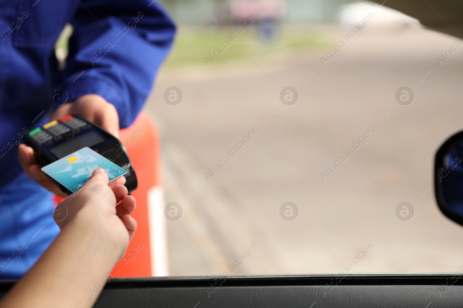 Photo of Woman sitting in car and paying with credit card at gas station, closeup