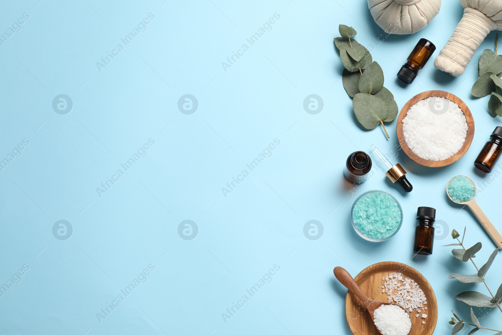 Photo of Different aromatherapy products and eucalyptus leaves on light blue background, flat lay. Space for text
