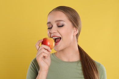 Photo of Young woman with apple on yellow background. Vitamin rich food