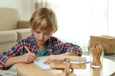 Photo of Little boy drawing at table indoors. Creative hobby