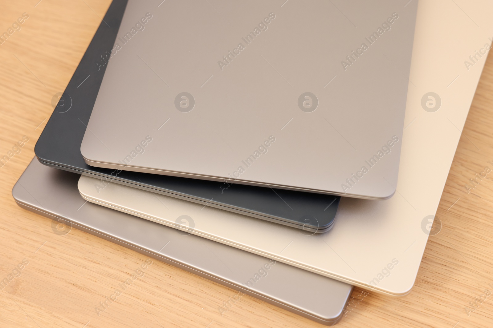 Photo of Different modern laptops on wooden table, closeup