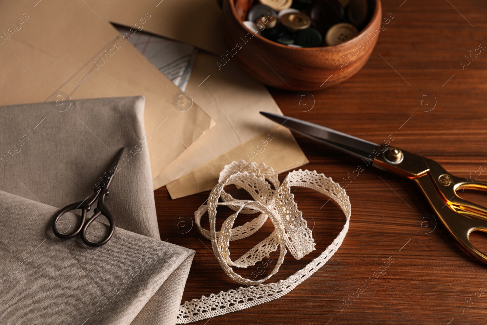 Photo of Set of sewing supplies and accessories with fabric on wooden table