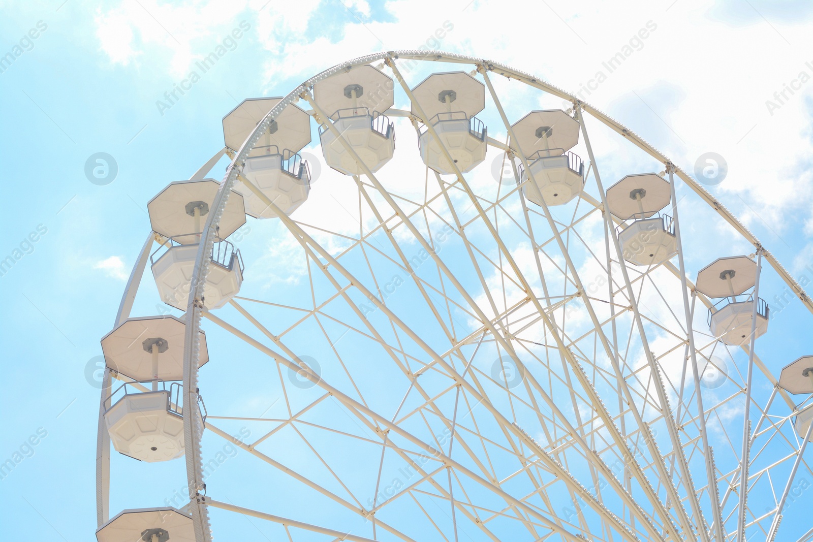 Photo of Large observation wheel against blue cloudy sky, low angle view