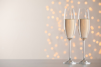 Glasses of champagne on grey table against blurred lights. Space for text