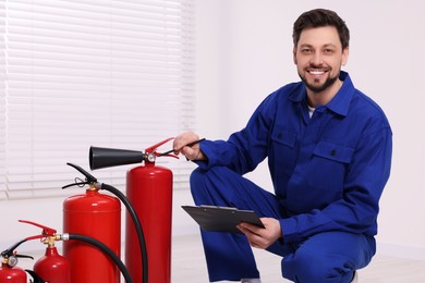 Man with clipboard checking fire extinguishers indoors