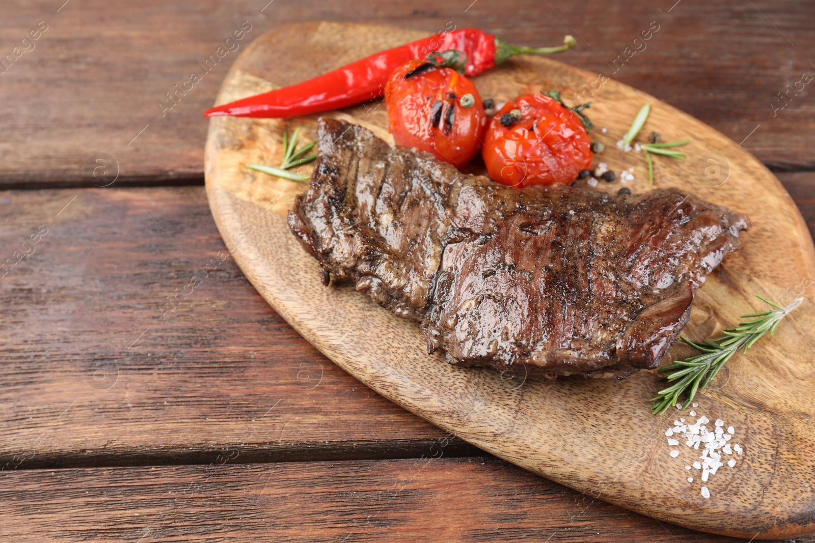 Photo of Delicious roasted beef meat, vegetables and spices on wooden table. Space for text