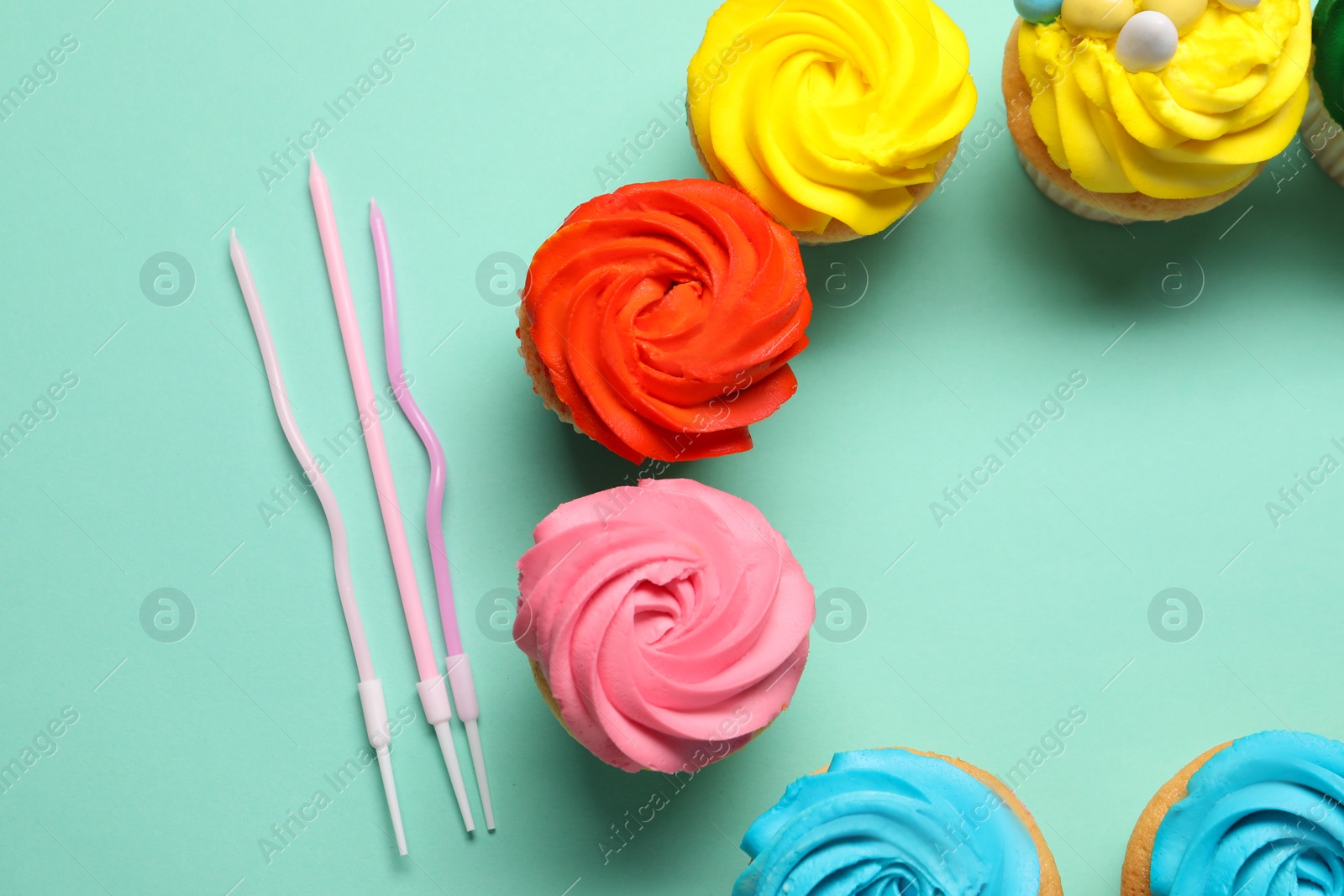 Photo of Delicious cupcakes with bright cream and candles on turquoise background, flat lay. Space for text