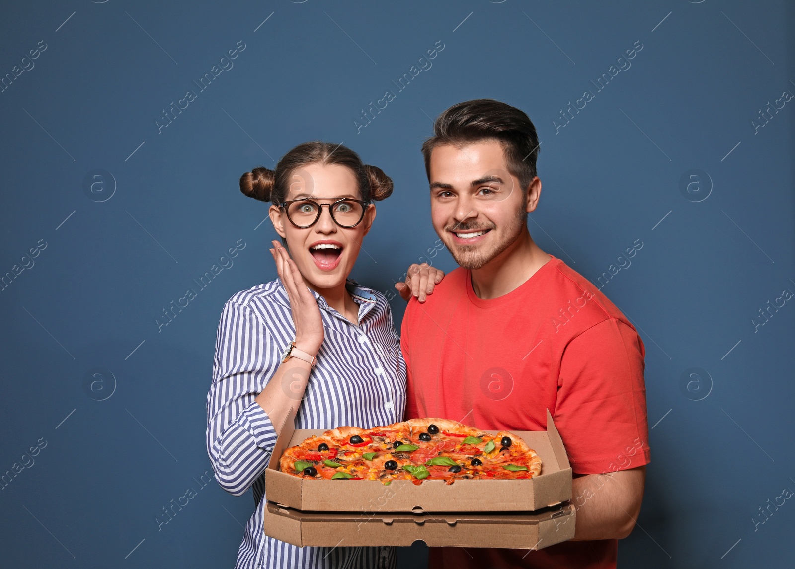 Photo of Attractive young couple with delicious pizza on color background