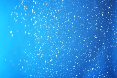 Photo of Snow flakes falling on blue background. Winter weather