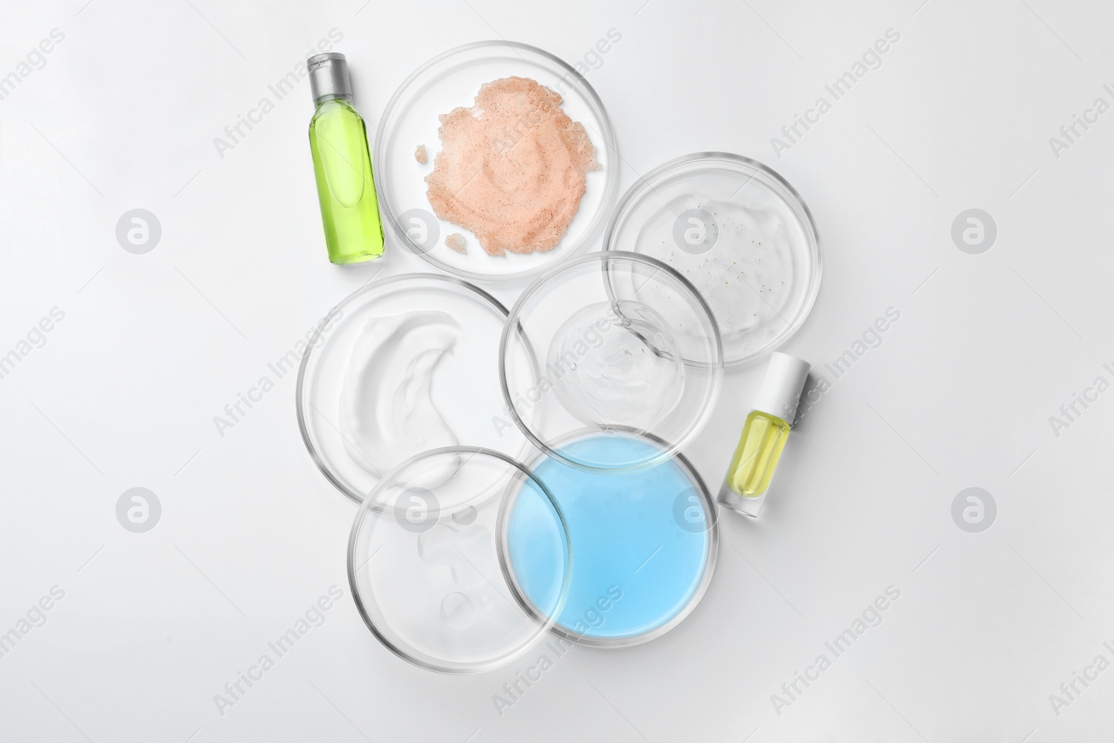 Photo of Many Petri dishes and cosmetic products on white background, top view