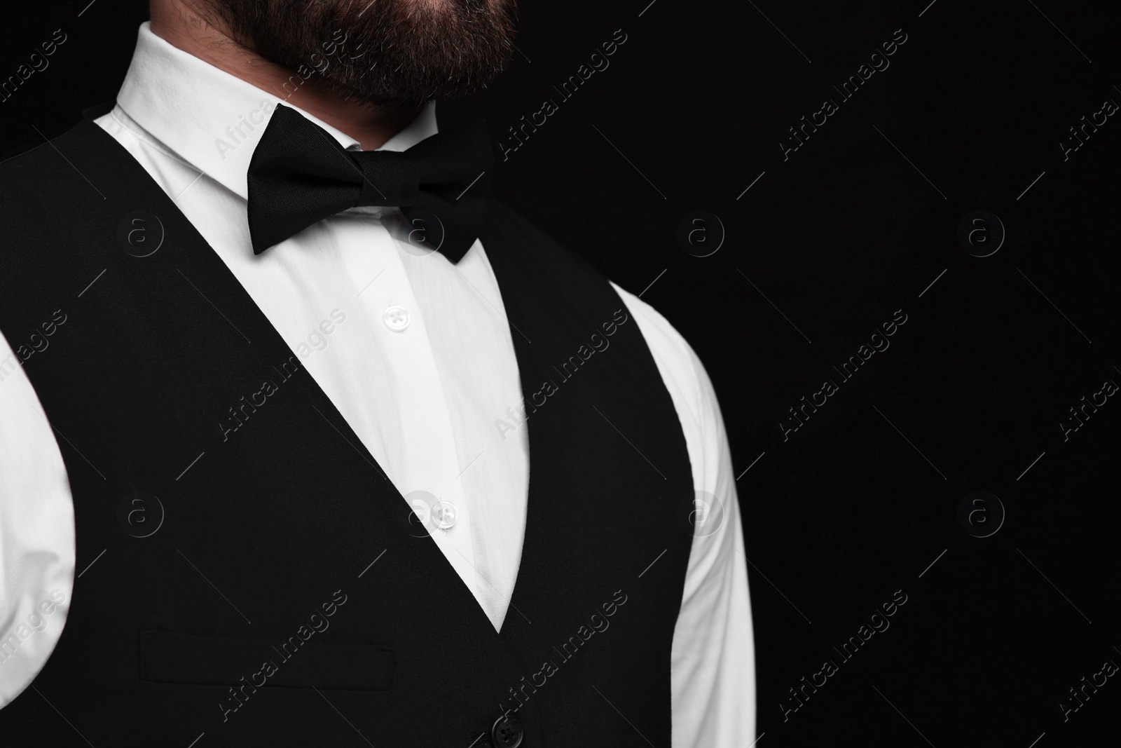 Photo of Man in shirt and bow tie on black background, closeup. Space for text