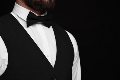 Man in shirt and bow tie on black background, closeup. Space for text