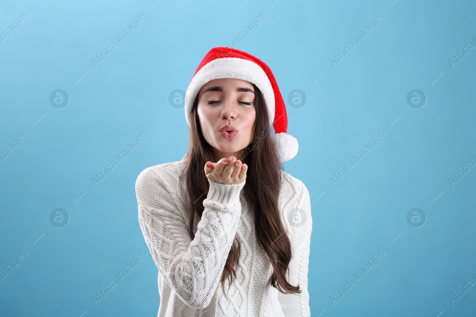 Photo of Beautiful woman wearing Santa Claus hat on light blue background