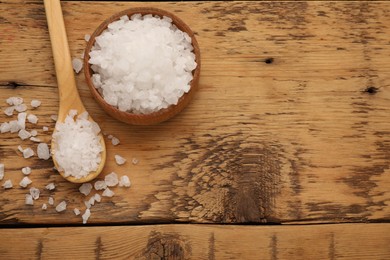 Photo of Bowl and spoon with sea salt on wooden table, flat lay. Space for text