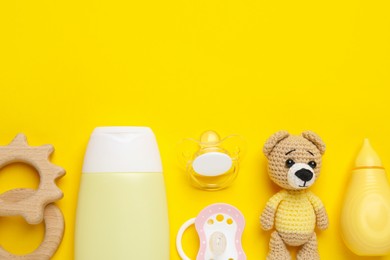 Photo of Flat lay composition with pacifiers and other baby stuff on yellow background. Space for text