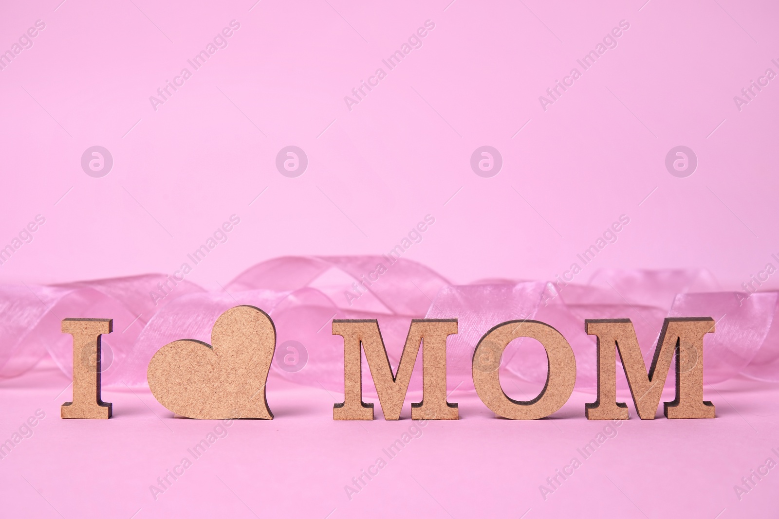 Photo of Phrase "I LOVE MOM" made of wooden letters and heart on color background. Happy Mother's Day