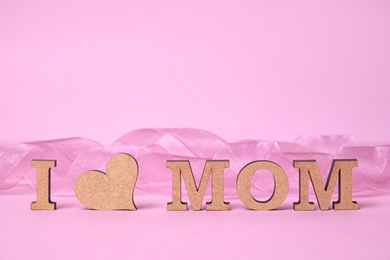 Photo of Phrase "I LOVE MOM" made of wooden letters and heart on color background. Happy Mother's Day