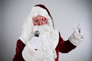 Photo of Santa Claus singing with microphone on light grey background. Christmas music