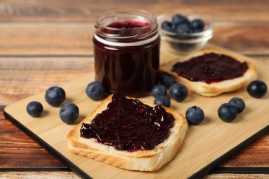 Photo of Delicious toasts with blueberry jam and fresh berries on wooden table