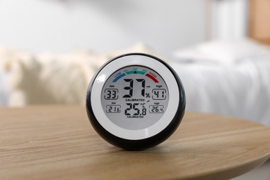 Digital hygrometer with thermometer on wooden table indoors