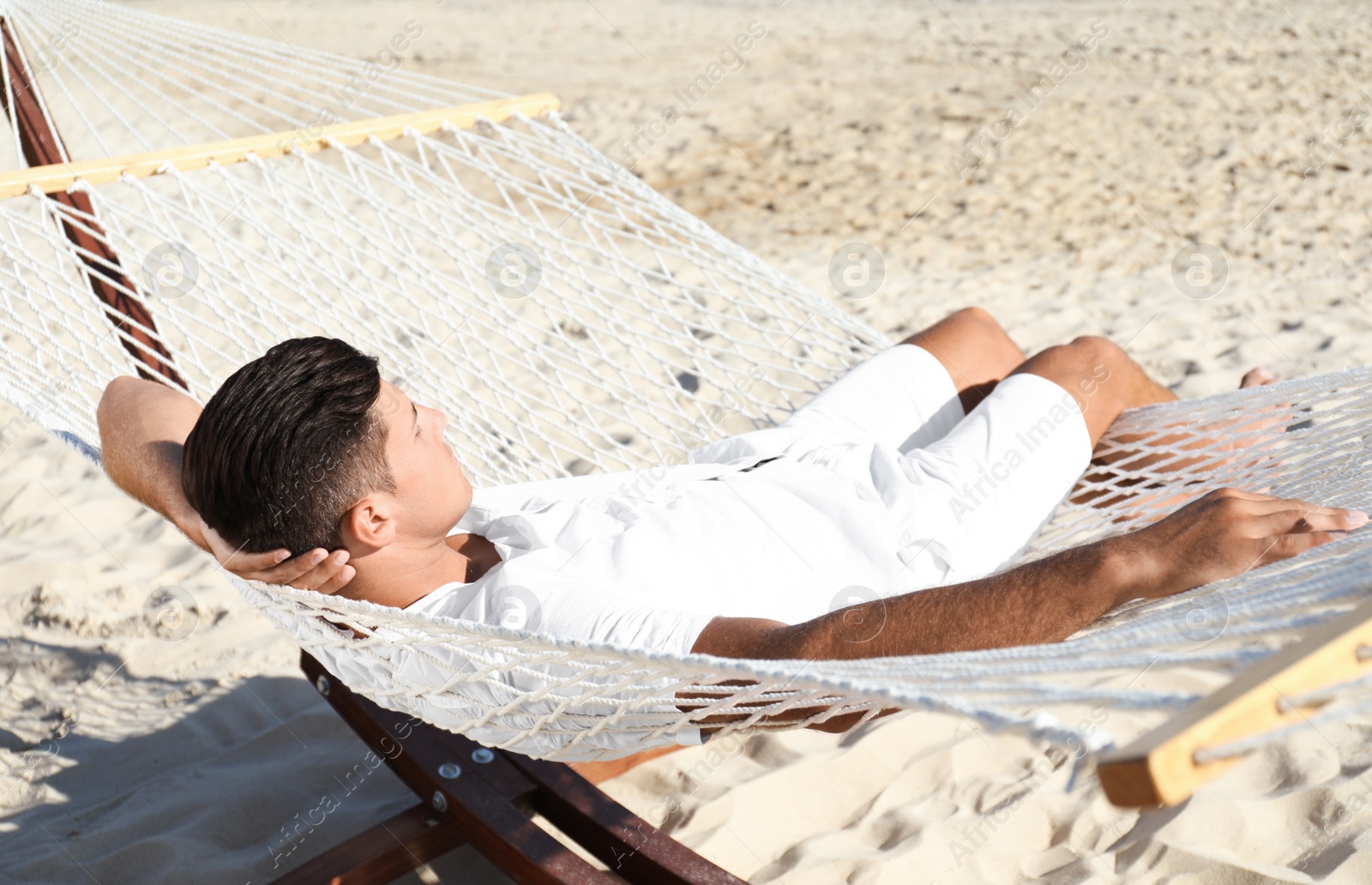 Photo of Man relaxing in hammock on beach. Summer vacation