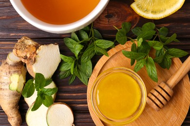 Flat lay composition of tea with mint, honey, lemon and ginger on wooden table
