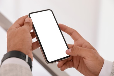 Man using mobile phone with empty screen indoors, closeup