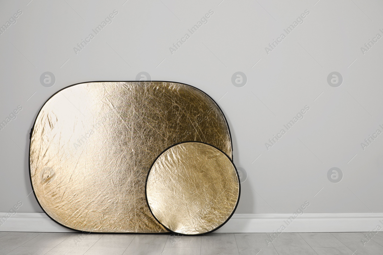 Photo of Studio reflectors near grey wall in room, space for text. Professional photographer's equipment