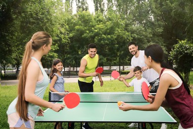 Photo of Happy families playing ping pong in park