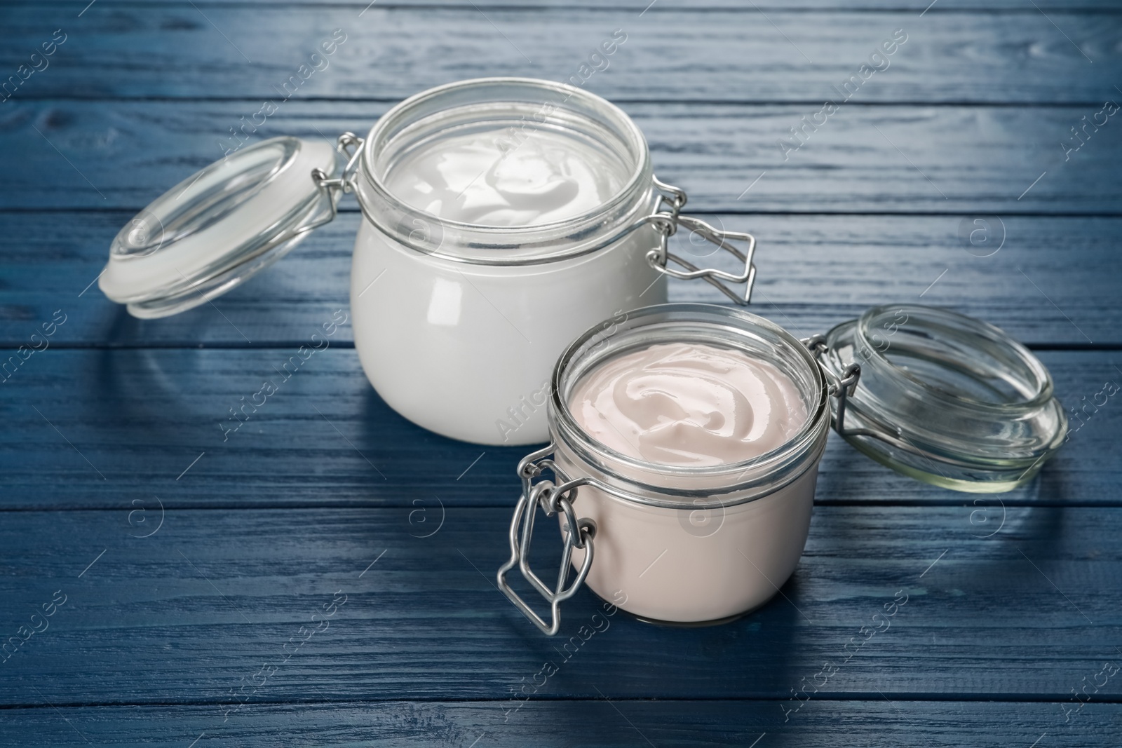 Photo of Jars of tasty organic yogurt on blue wooden table