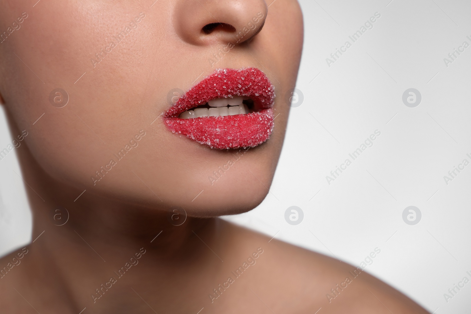 Photo of Young woman with lips covered in sugar on light background, closeup. Space for text