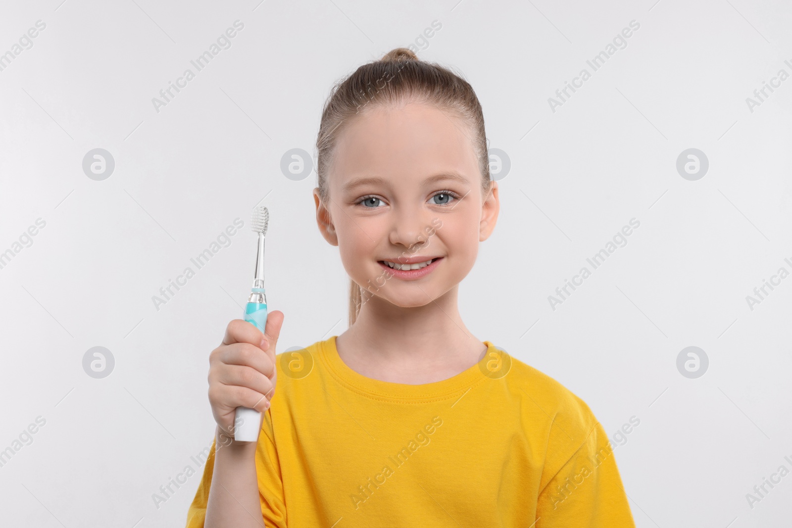 Photo of Happy girl holding electric toothbrush on white background