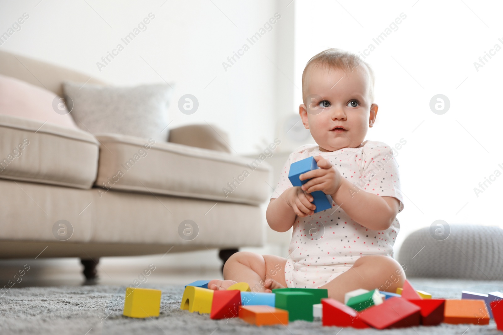 Photo of Cute baby girl playing with building blocks in room. Space for text