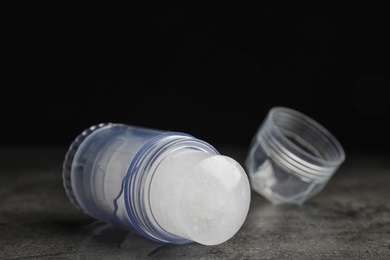 Natural crystal alum deodorant and cap on grey table against black background