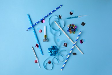 Photo of Party blower and festive decor on light blue background, flat lay