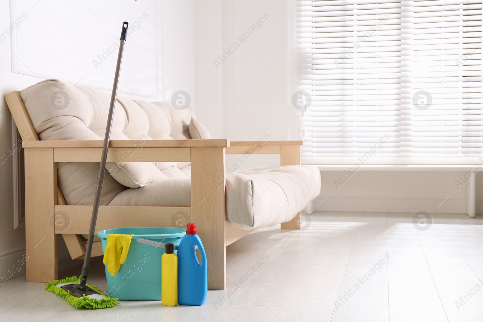 Photo of Floor mop, cleaning detergents and bucket with gloves in living room