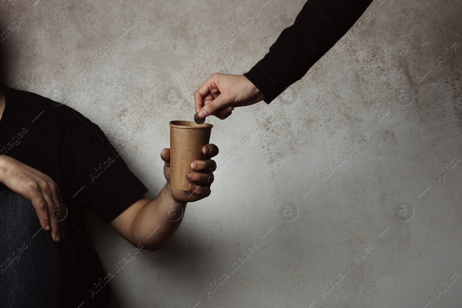 Photo of Poor man receiving coin from woman on grey background with space for text, closeup