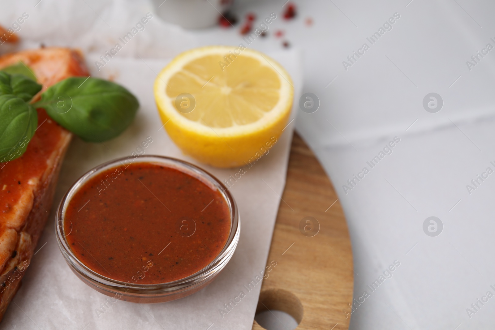 Photo of Fresh marinade, fish, lemon and basil on white tiled table, closeup. Space for text