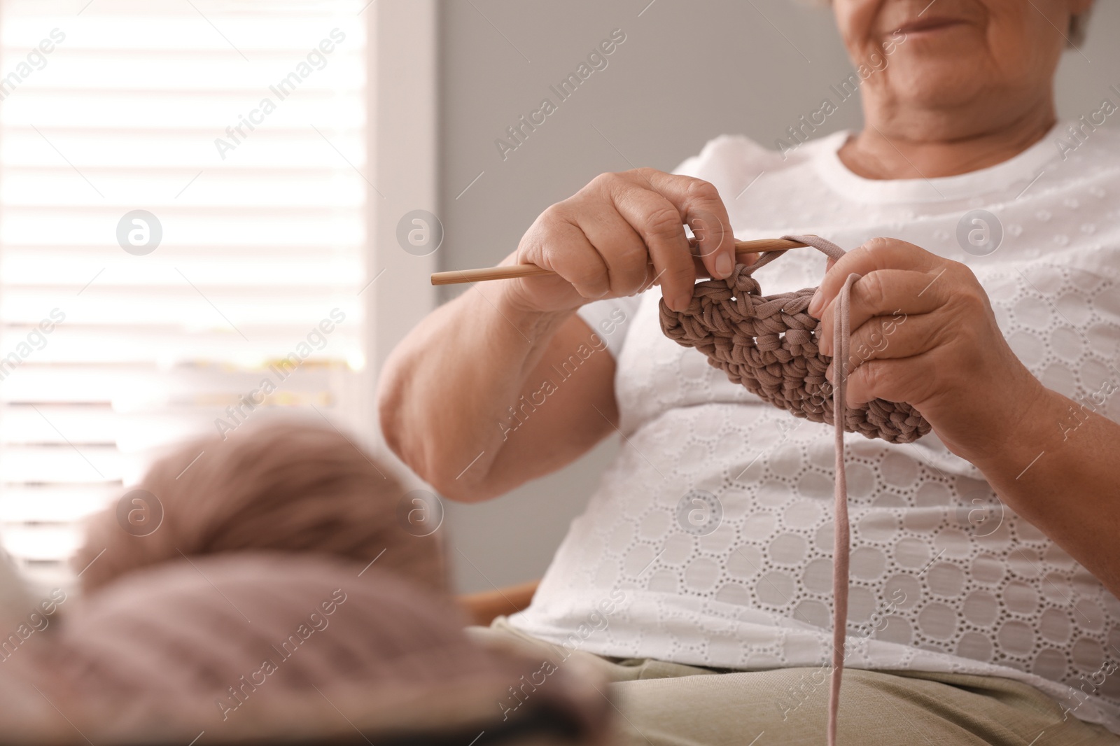 Photo of Elderly woman knitting at home, closeup. Creative hobby