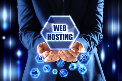 Image of Man showing virtual icon with phrase Web Hosting on dark background, closeup