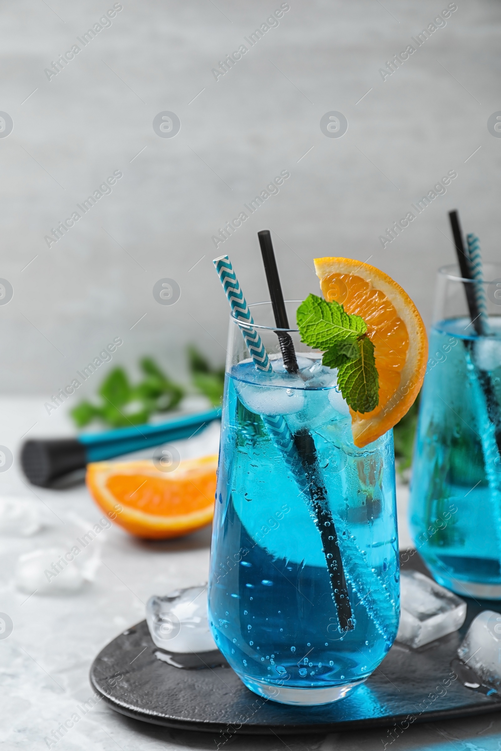 Photo of Glass of delicious Blue Lagoon cocktail with ice on light table