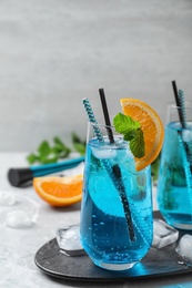 Photo of Glass of delicious Blue Lagoon cocktail with ice on light table