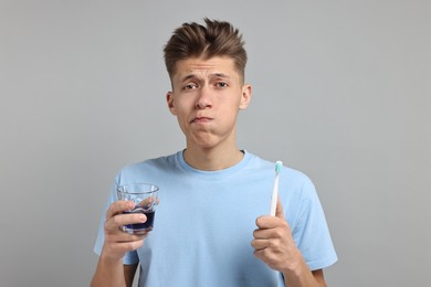 Photo of Young man using mouthwash on light grey background