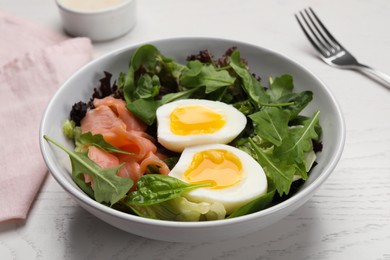 Photo of Delicious salad with boiled egg, salmon and arugula on white wooden table, closeup