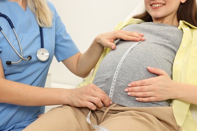 Pregnancy checkup. Doctor measuring patient's tummy in clinic, closeup