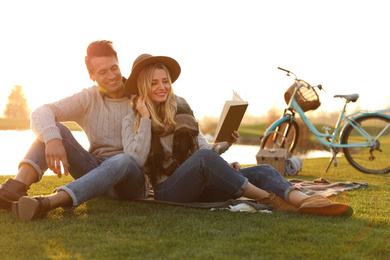 Happy young couple reading book while having picnic outdoors