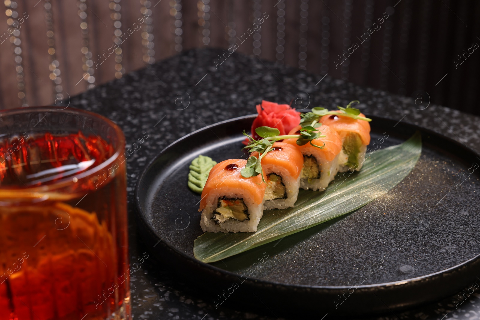 Photo of Delicious sushi rolls served with alcoholic Negroni cocktail on dark table, closeup
