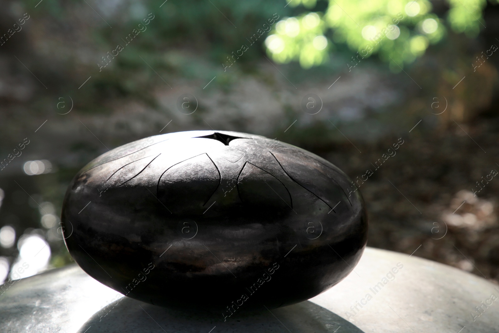 Photo of Steel tongue drum on stone outdoors. Percussion musical instrument